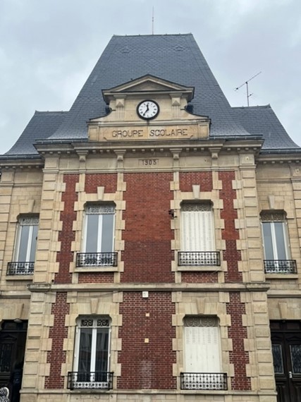 Façade ancienne d’un groupe scolaire avec horloge.
