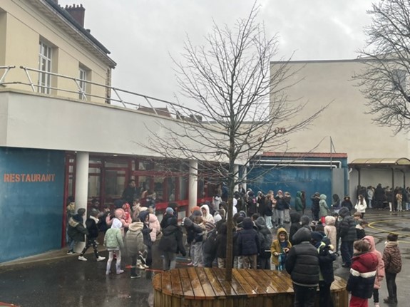 Cour d’école sous la pluie avec de nombreux enfants.