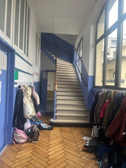 Escalier d’école avec manteaux et sacs le long du mur.