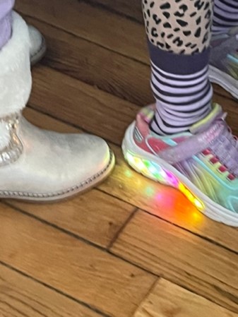 Chaussure lumineuse et botte sur un parquet.