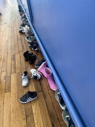 Rangée de chaussures posées au sol contre un mur.